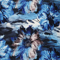 A close-up of a floral fabric pattern featuring large watercolor-style flowers in shades of blue, navy, and beige on a white background.